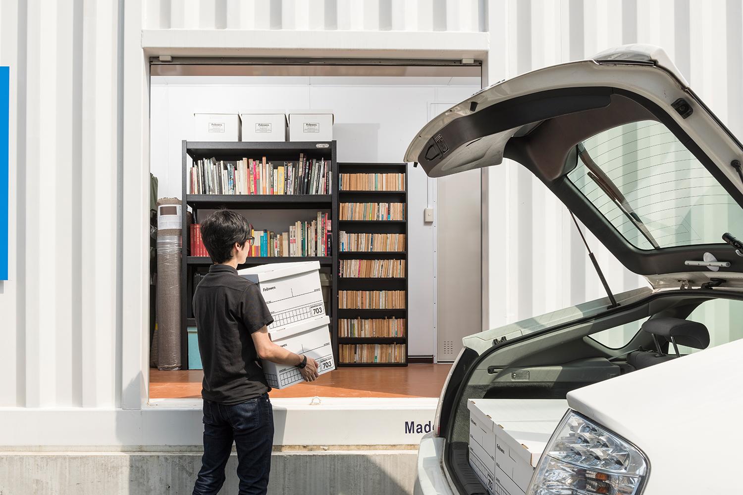 車からトランクルームに荷物を運んでいる人