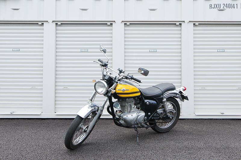 屋内型バイク駐車場の利用イメージ。シャッター付きコンテナ前にバイクが駐車されている様子